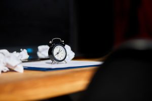 Modern workplace, wooden office desk in hardlight, sunligt with clock, sheet of paper, laptop, notebook, crumpled paper balls, Change Your Mindset, plan B, time to set new goals, business and personal plans