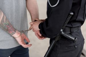 cropped shot of policewoman with truncheon handcuffing bandit