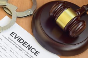 Justice mallet and evidence report blank document for crime scene investigation with police handcuffs close up