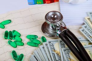 Medical phonendoscope lies on cardiogram gradiented background and pills and dollars Healthcare concept. Closeup.