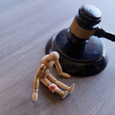 Bandage wrap with blood stain, wooden doll and judge gavel. Personal injury law concept.