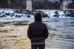 man in a hood looking at the river recovering from a personal injury case