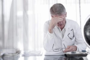 Doctor rubbing his forehead in office