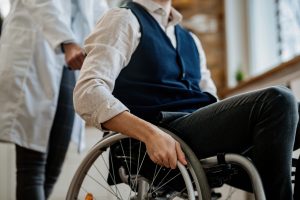 Close-up of unrecognizable man in wheelchair with a doctor.