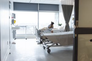 African american girl patient sitting on bed in patient room at hospital, copy space. Hospital, childhood, medicine and healthcare, unaltered.