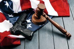 judge gavel, gun and american flag on a wood table