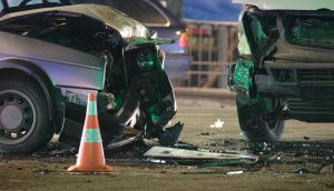 Damaged in heavy car accident vehicles after collision on city street crash site at night. Road safety and insurance concept.