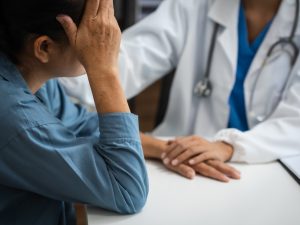 Mature chinese woman in consultation with a doctor with abdominal pain. depression.